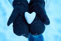 An abstract photo of love. A pair of lovers holding each other`s hands and a heart-shaped snowball in their hands