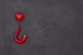 Abstract picture of a tomato and pepper in the shape of a hook. Black background. There is a place for text