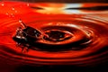 Abstract picture of water drop with splash and ripples on nice red orange background Royalty Free Stock Photo