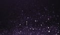 Abstract purple dust dark background. Bokeh blur, glitter defocused on black background. Royalty Free Stock Photo