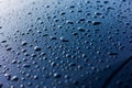 Abstract rain or water drops different size on a blue car hood surface with shiny reflections. Water droplets on dark Royalty Free Stock Photo