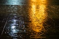 Abstract raindrop and spatter water on pavement floor with yellow and white light reflection at night Royalty Free Stock Photo