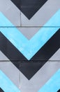 Abstract repeating blue, black and grey arrow-shaped lines on industrial building wall. Vertical photo background