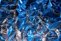 Abstract rumpled foil texture background. Futuristic bright neon blue and silver texture