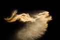 Abstract sand cloud.Golden colored sand splash agianst dark background.Yellow sand fly wave in the air. Royalty Free Stock Photo