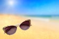 Abstract sea background. Abstract tropical sandy summer beach background with bokeh lights on light blue sky, sun and sunglasses. Royalty Free Stock Photo