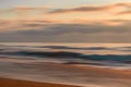 Abstract seascape in light pink, blue, and orange colors. Sand beach, blue ocean and cloudy sky at sunset Royalty Free Stock Photo