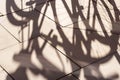 Abstract shadow of bicycle wheels on a tiled ground