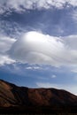 Abstract shaped towering dense wave like cumulus cloud over mountain peak on Canary Islands, Tenerife