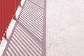 A red railing casting straight shadows over cement floor Royalty Free Stock Photo