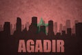 Abstract silhouette of the city with text Agadir at the vintage moroccan flag