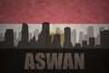 Abstract silhouette of the city with text Aswan at the vintage egyptian flag