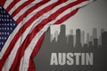 Abstract silhouette of the city with text austin near waving national flag of united states of america on a gray background