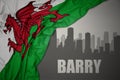 Abstract silhouette of the city with text Barry near waving national flag of wales on a gray background