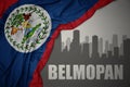 Abstract silhouette of the city with text Belmopan near waving national flag of belize on a gray background. 3D illustration