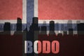 Abstract silhouette of the city with text Bodo at the vintage norwegian flag