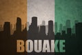 Abstract silhouette of the city with text Bouake at the vintage ivorian flag