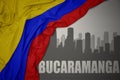 Abstract silhouette of the city with text Bucaramanga near waving national flag of colombia on a gray background