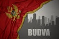 Abstract silhouette of the city with text Budva near waving national flag of montenegro on a gray background