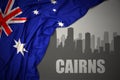 Abstract silhouette of the city with text Cairns near waving national flag of australia on a gray background