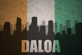 Abstract silhouette of the city with text Daloa at the vintage ivorian flag