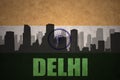 abstract silhouette of the city with text Delhi at the vintage indian flag