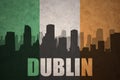 Abstract silhouette of the city with text Dublin at the vintage irish flag