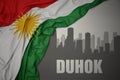 Abstract silhouette of the city with text Duhok near waving national flag of kurdistan on a gray background.3D illustration