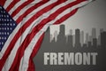 Abstract silhouette of the city with text Fremont near waving national flag of united states of america on a gray background. 3D