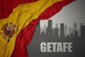 Abstract silhouette of the city with text Getafe near waving national flag of spain on a gray background