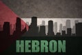 Abstract silhouette of the city with text Hebron at the vintage palestinian flag