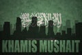 Abstract silhouette of the city with text Khamis Mushait at the vintage saudi arabia flag