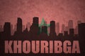 Abstract silhouette of the city with text Khouribga at the vintage moroccan flag