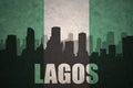 Abstract silhouette of the city with text Lagos at the vintage nigerian flag