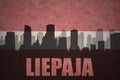Abstract silhouette of the city with text Liepaja at the vintage latvian flag