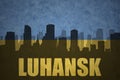 Abstract silhouette of the city with text Luhansk at the vintage ukrainian flag