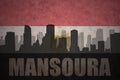 Abstract silhouette of the city with text Mansoura at the vintage egyptian flag