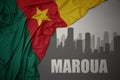 Abstract silhouette of the city with text Maroua near waving colorful national flag of cameroon on a gray background Royalty Free Stock Photo