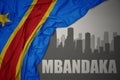 Abstract silhouette of the city with text Mbandaka near waving colorful national flag of democratic republic of the congo on a