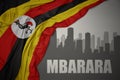 Abstract silhouette of the city with text Mbarara near waving colorful national flag of uganda on a gray background