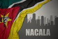 Abstract silhouette of the city with text Nacala near waving colorful national flag of mozambique on a gray background Royalty Free Stock Photo