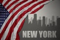 Abstract silhouette of the city with text New York near waving national flag of united states of america on a gray background Royalty Free Stock Photo
