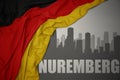 Abstract silhouette of the city with text Nuremberg near waving national flag of germany on a gray background