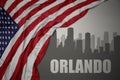 Abstract silhouette of the city with text Orlando near waving national flag of united states of america on a gray background. 3D Royalty Free Stock Photo