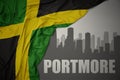 Abstract silhouette of the city with text Portmore near waving national flag of jamaica on a gray background. 3D illustration