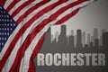 Abstract silhouette of the city with text Rochester near waving national flag of united states of america on a gray background. 3D Royalty Free Stock Photo