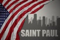 Abstract silhouette of the city with text Saint Paul near waving national flag of united states of america on a gray background.