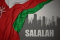 Abstract silhouette of the city with text Salalah near waving national flag of oman on a gray background.3D illustration