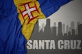 Abstract silhouette of the city with text Santa Cruz near waving national flag of madeira on a gray background