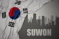 Abstract silhouette of the city with text Suwon near waving national flag of south korea on a gray background